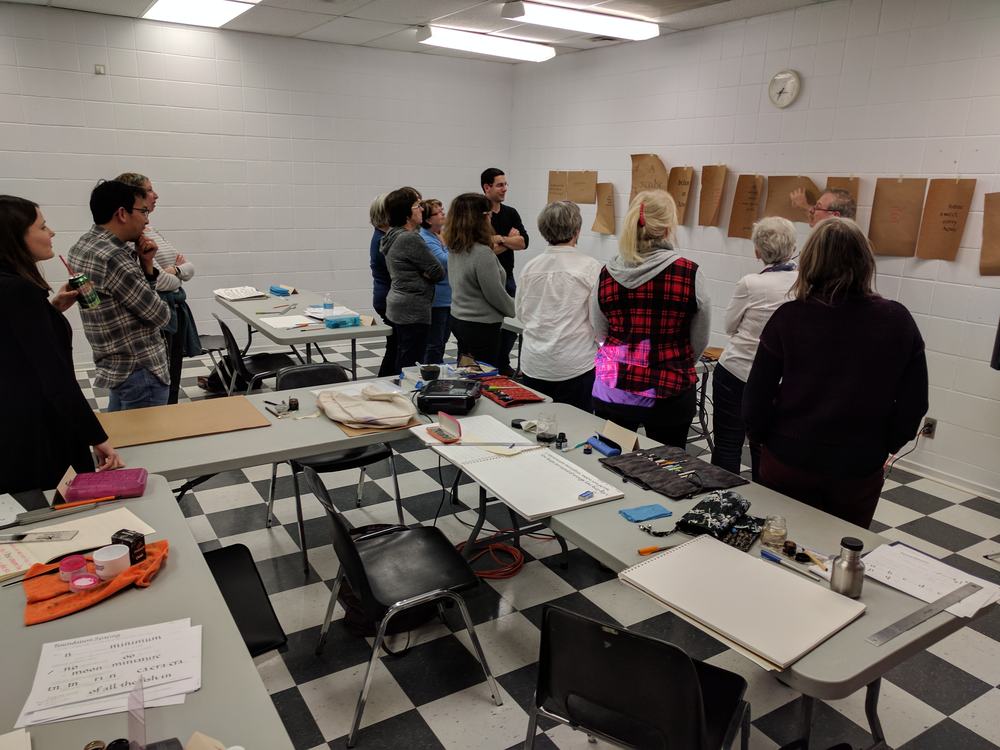 Students reviewing their short quotes written on Kraft paper with instructor Rick Draffin